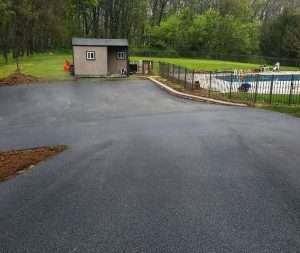 A paved driveway with a pool in the background.