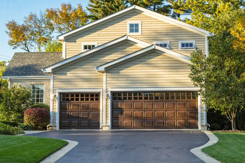 A house with two garage doors and an asphalt driveway.