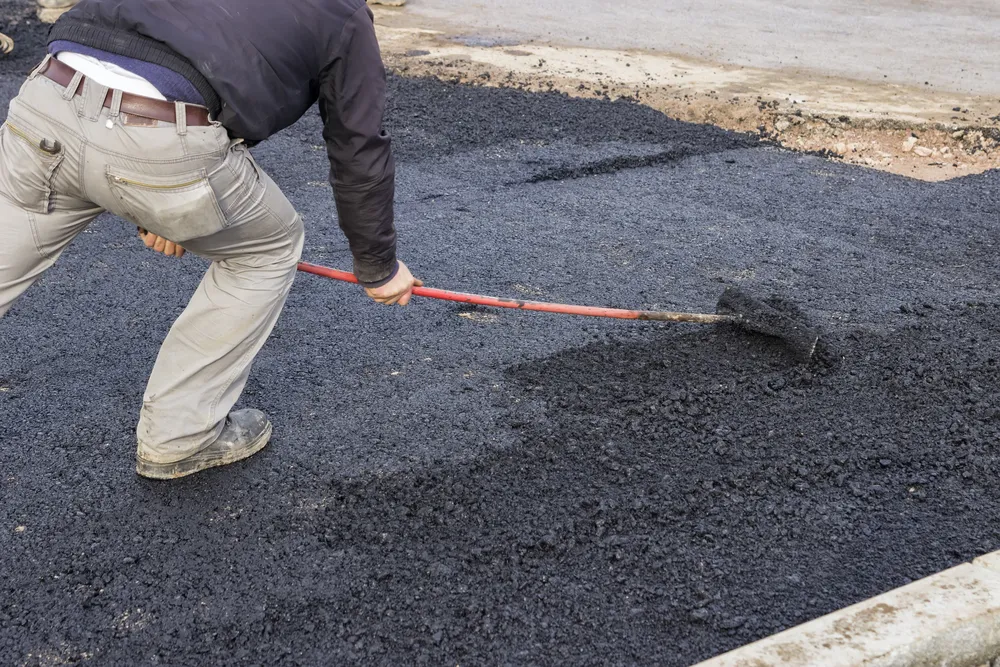 Expert Paver resurfacing an asphalt drive way by adding a fresh layer of asphalt.