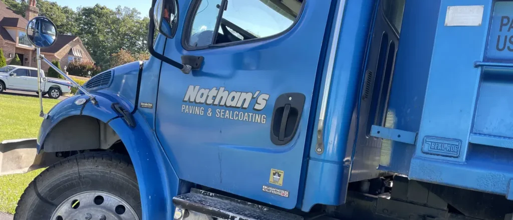 A close-up of the driver's side of a blue truck labeled "Nathan's Paving & Sealcoating