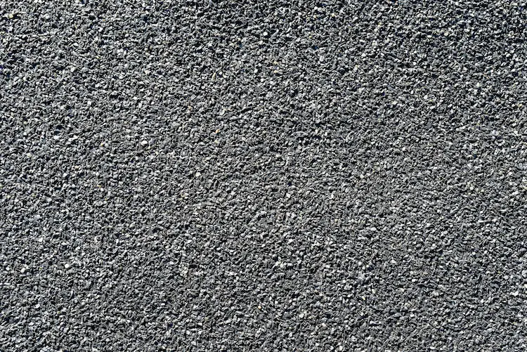 A close-up image of a gravel road made with asphalt paving materials.