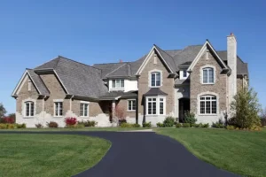 A large house with a freshly sealed asphalt driveway leading to it.