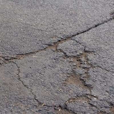 A detailed shot of asphalt repair work, showing a fresh patch on a cracked driveway.