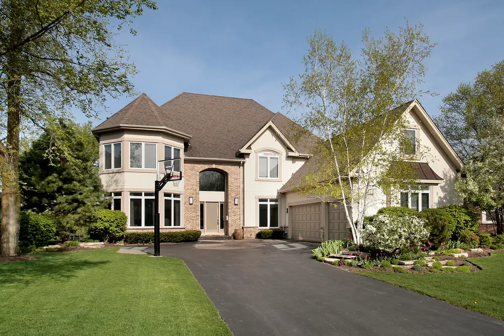 A large home with an asphalt driveway leading to it.