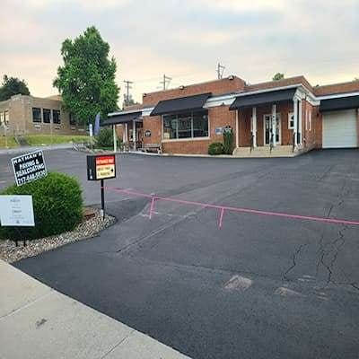 The asphalt parking lot of a business with a sign on it.