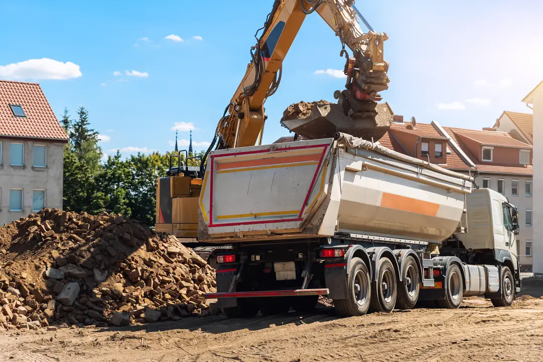 An excavator loading debris into a truck at a construction site.