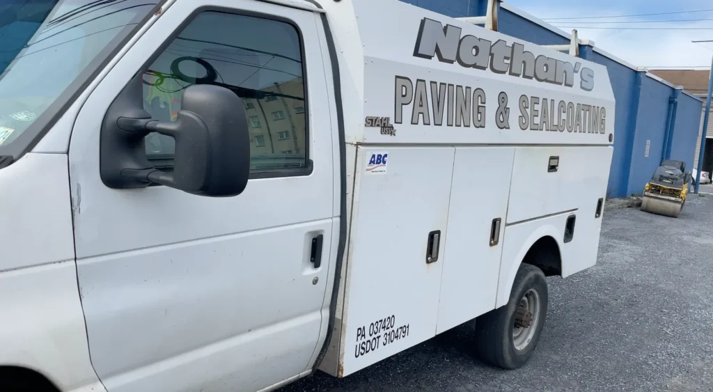 A logo for Nathan Paving, featuring the company name in bold letters with a pavement texture background, emphasizing their role as a local paving and sealing contractor in Carlisle.