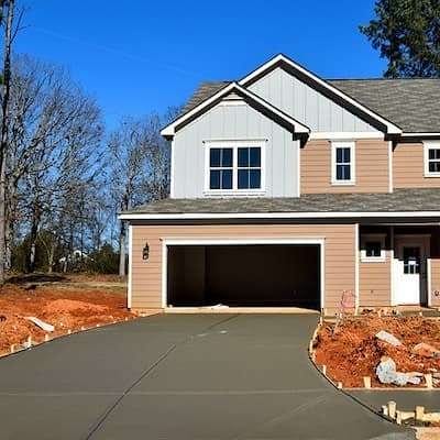 A new driveway installation with fresh asphalt, blending with the surrounding lawn.