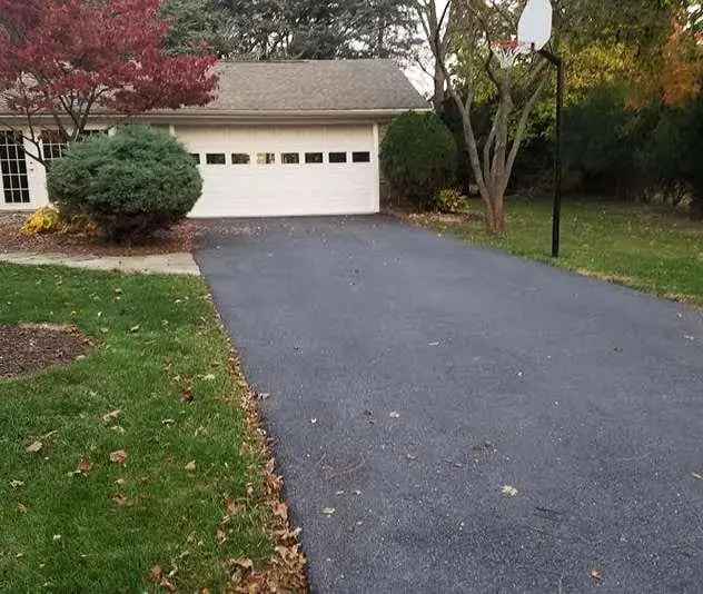 A large driveway before seal coating, showing uneven surface and worn-out asphalt.