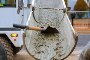 A man is pouring concrete into a truck.|Pouring cement over concrete floor.|A truck is pouring concrete over an existing asphalt on a city street.