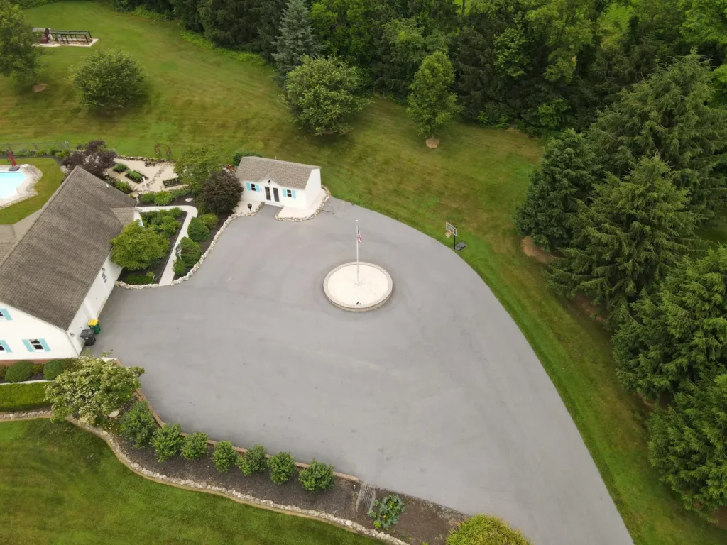 A before image of a worn asphalt driveway in Carlisle, showing cracks and faded patches. The surface appears muddy and uneven, indicating the need for sealing and maintenance.